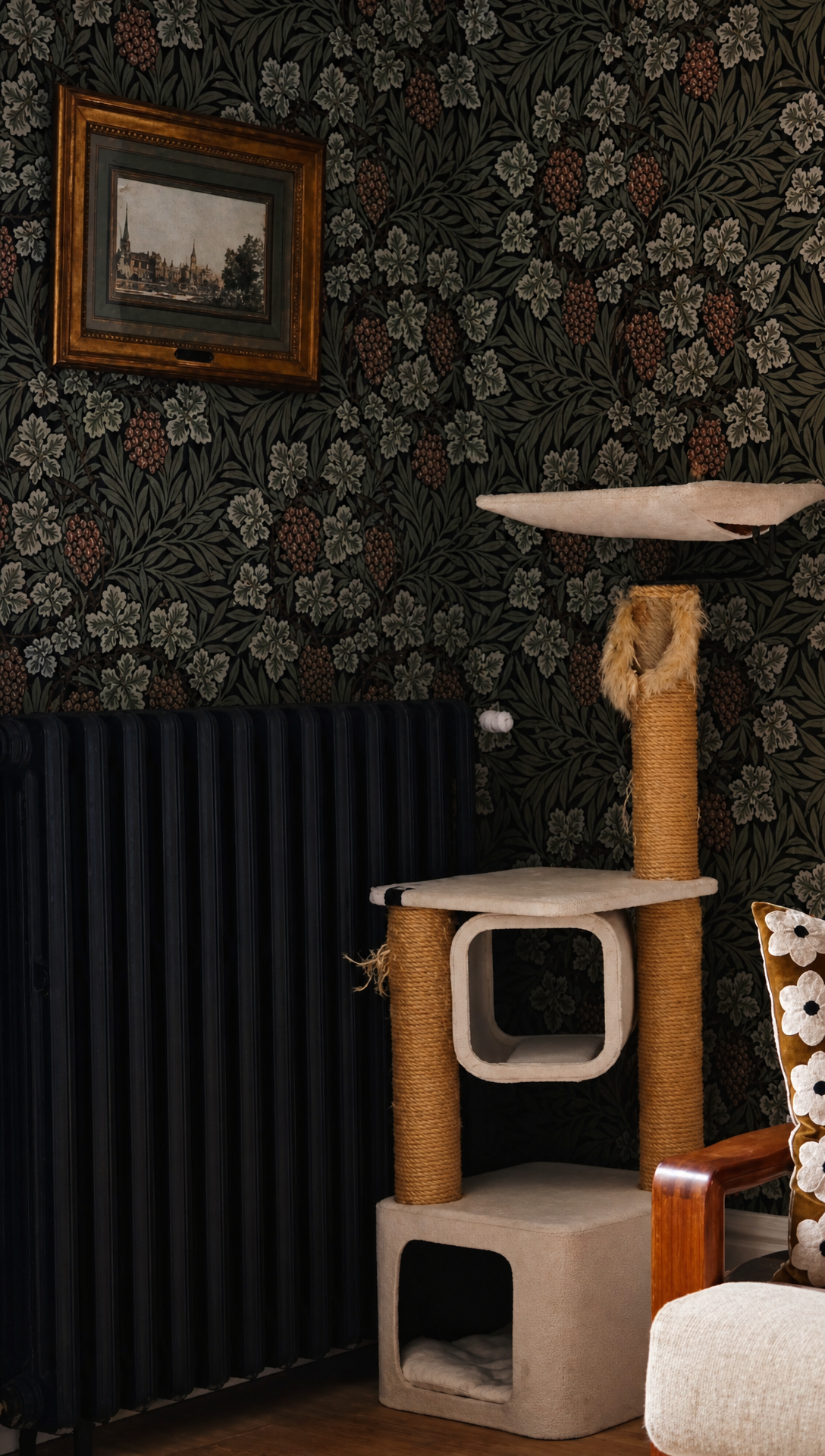 The living room corner with dark floral wallpaper, a black radiator and the old beige cat tree
