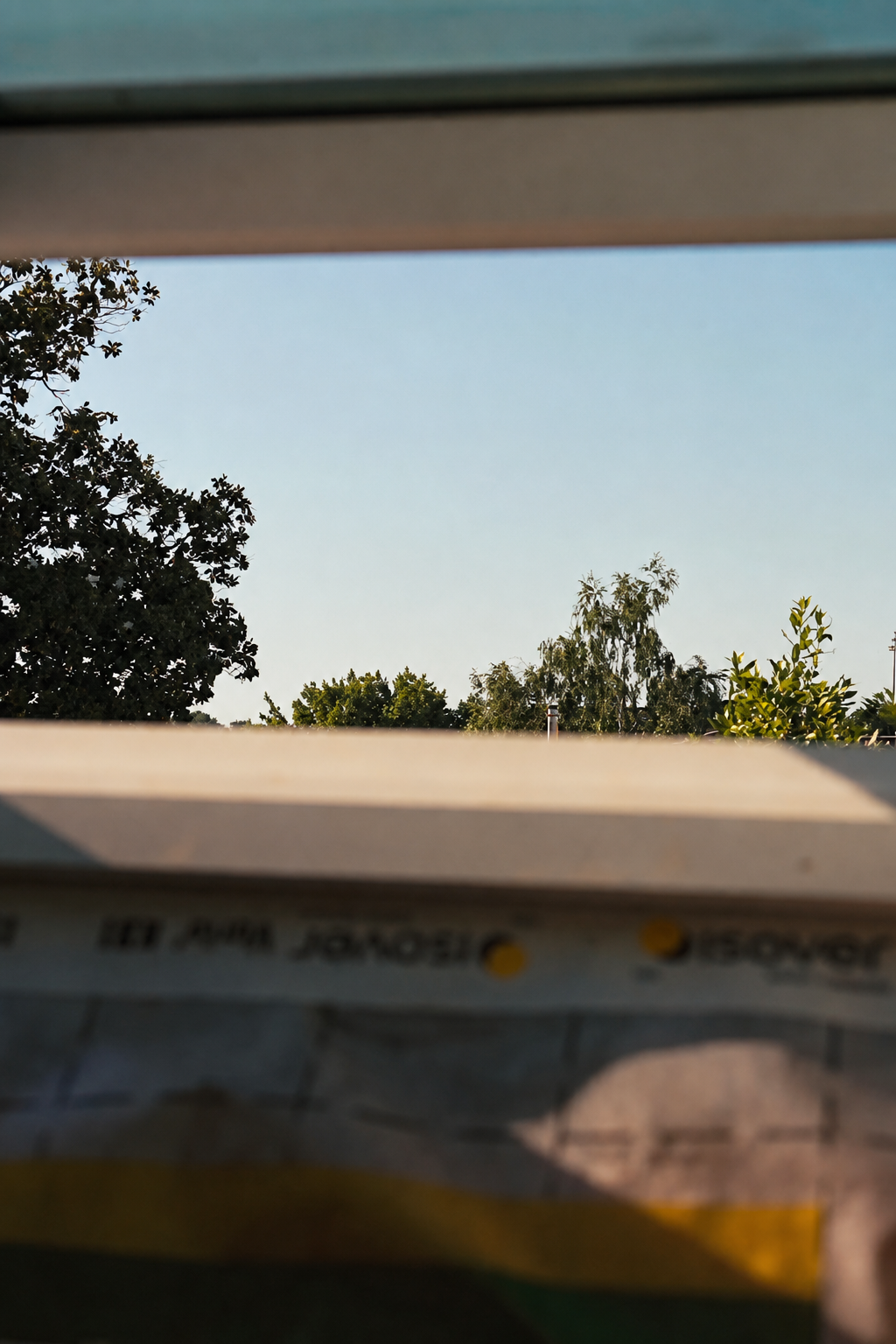 Blue sky and treetops seen through the open attic roof window