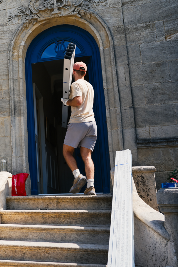 The limestone facade of the Bordeaux chartreuse with materials being carried up the front steps to the open blue door
