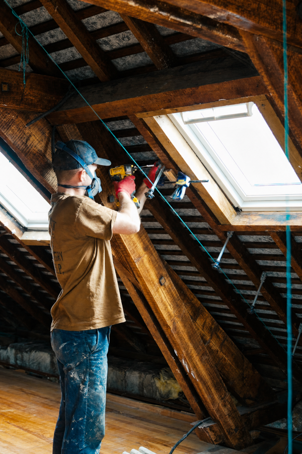 Hugo drilling overhead between two skylights in the exposed timber roof of the attic