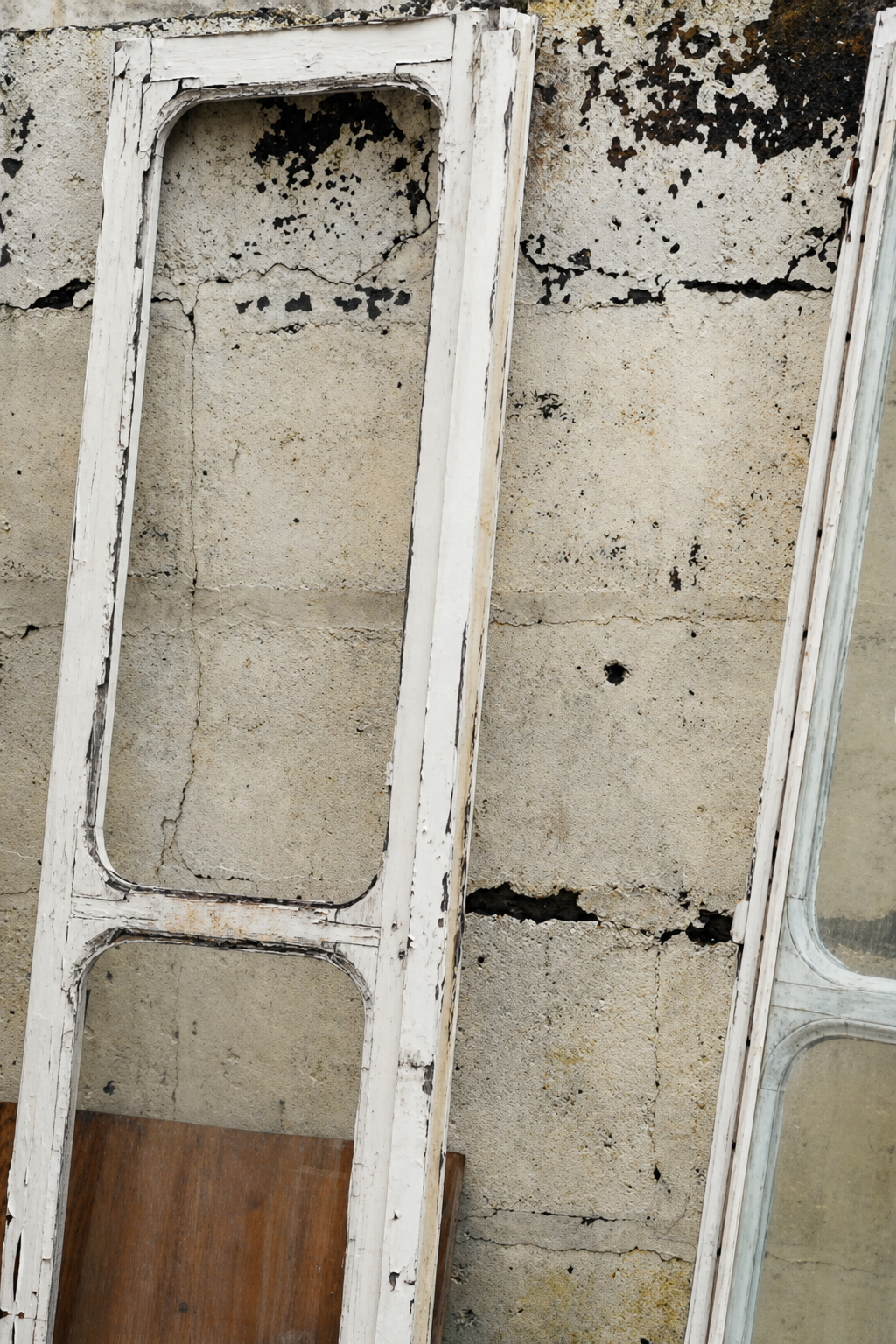 The old white window frames leaning against the weathered garden wall
