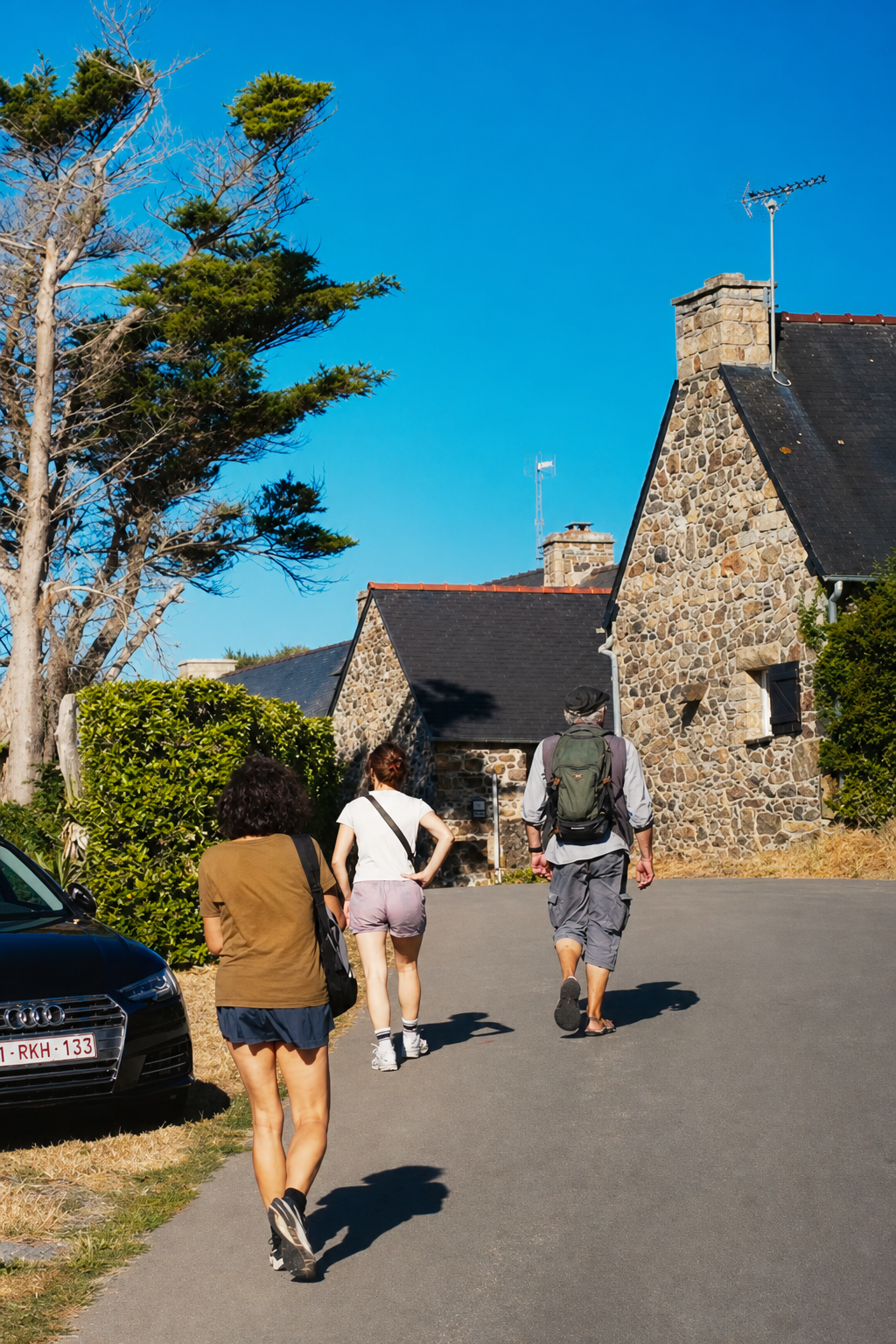 Walking down a narrow lane between granite houses in a Breton village on a sunny day