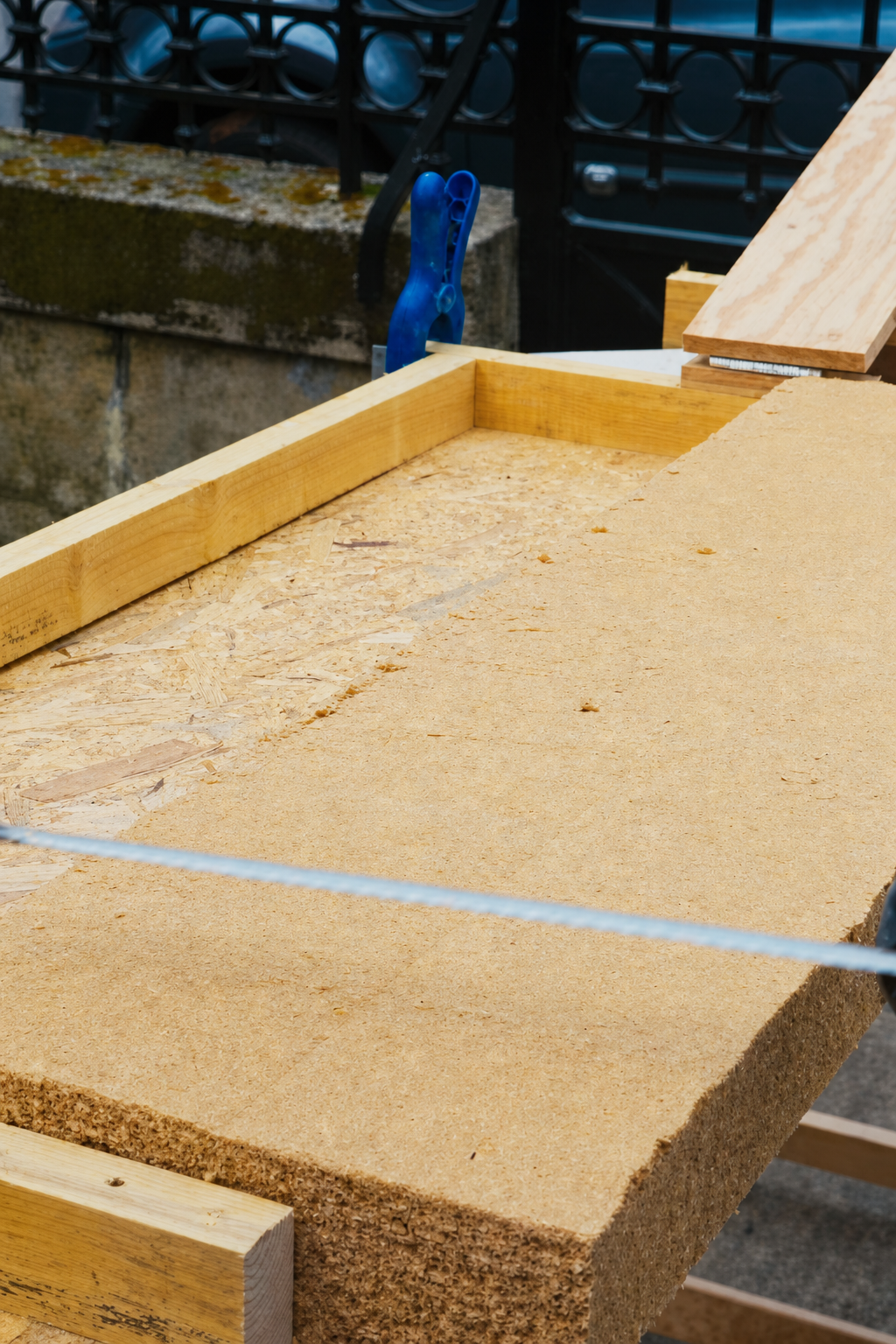 Close up of a hand saw cutting through a wood fibre batt on the jig