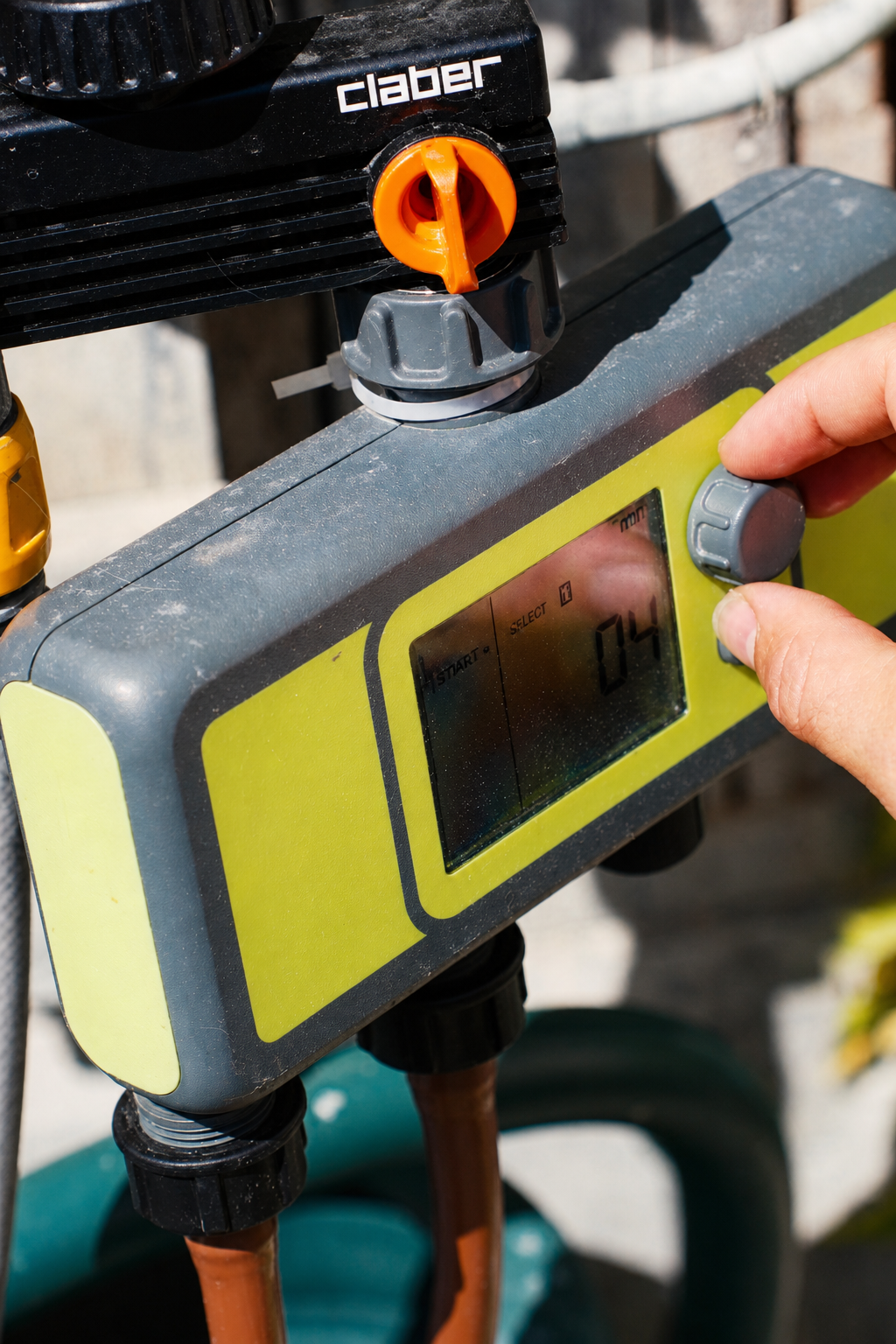 Hand adjusting an electronic watering timer connected to two irrigation zones