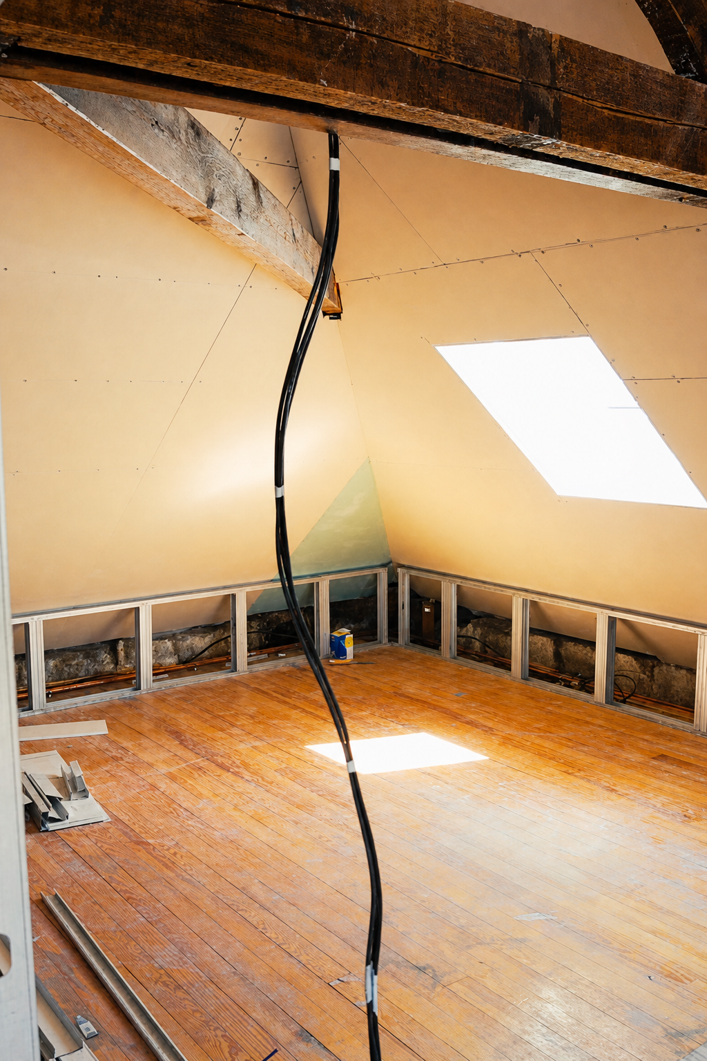 Newly framed room corner in the attic with a skylight and warm evening light