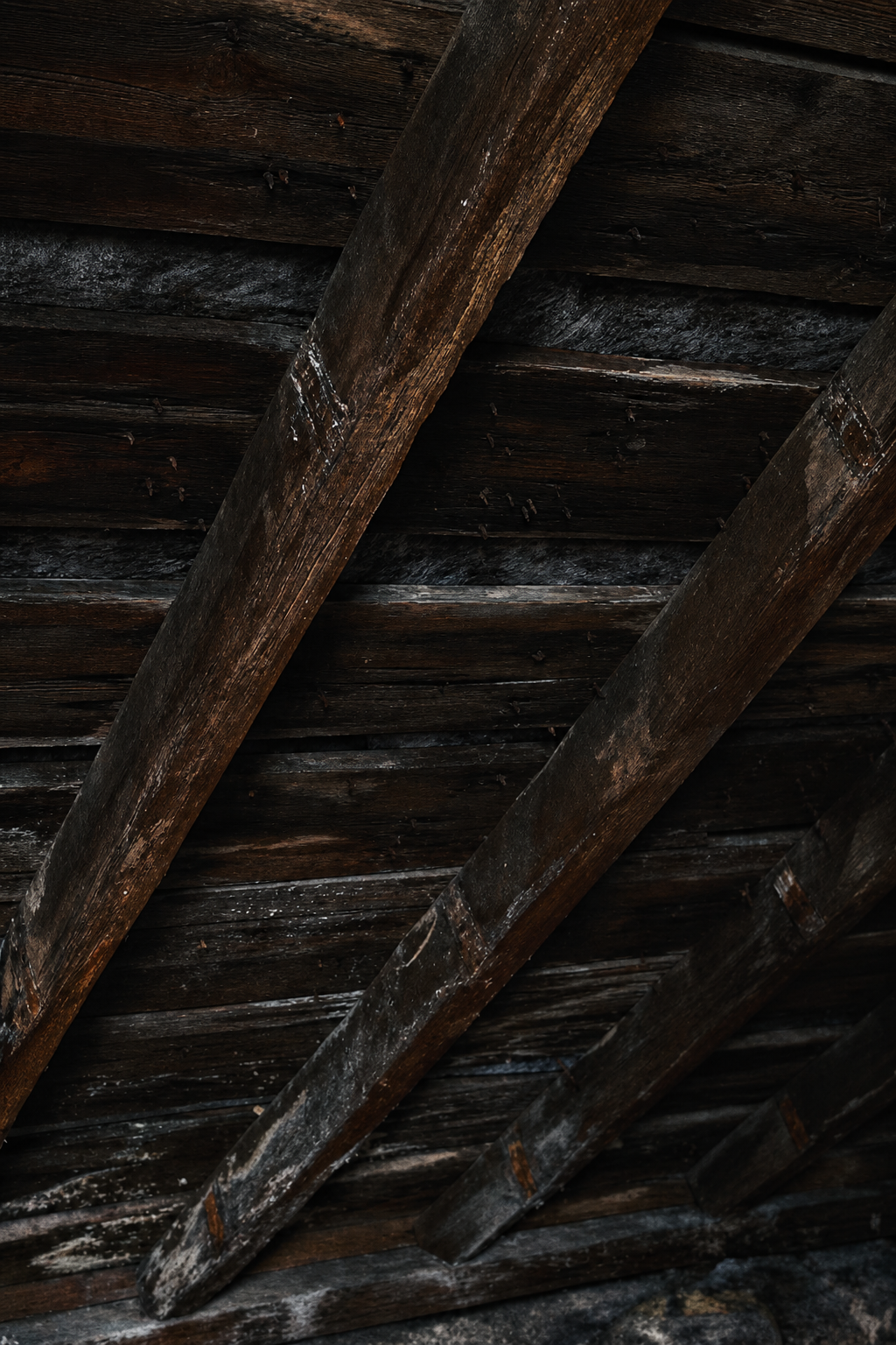 The dark twisted oak beams of the attic roof seen from below