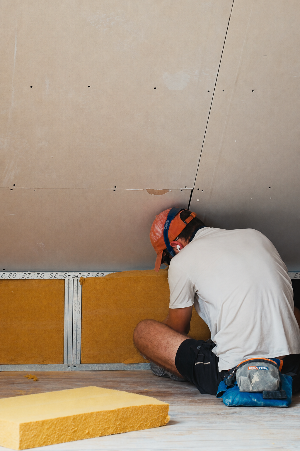 Hugo crouched in the corner of the attic fitting insulation panels into the low stud bays under the sloping ceiling