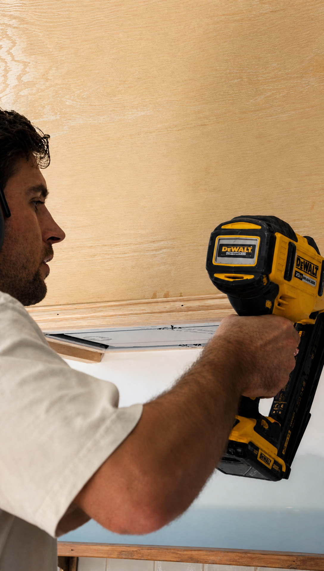 Hugo fixing a length of moulding to the bottom edge of the plywood hood with a brad nailer