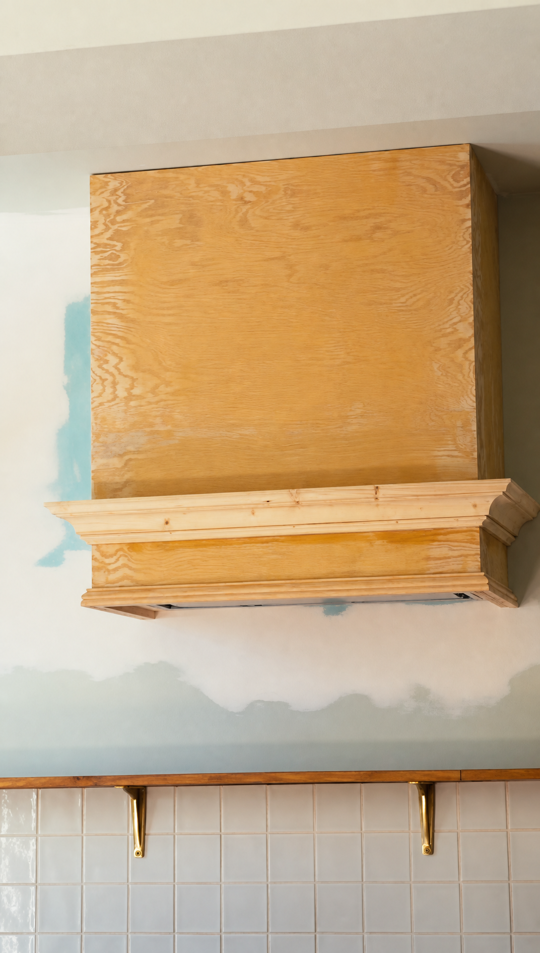 The plywood range hood with its bottom moulding fitted, still in bare wood above the white tiled splashback