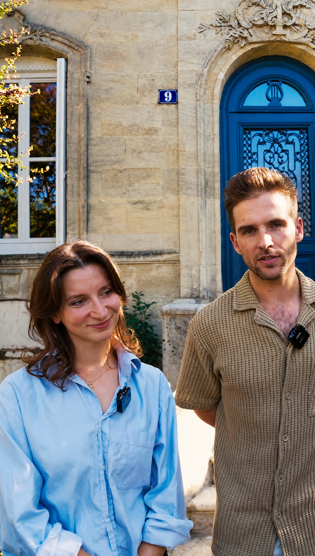 Romy and Hugo standing in front of the blue arched front door of their stone house in Bordeaux
