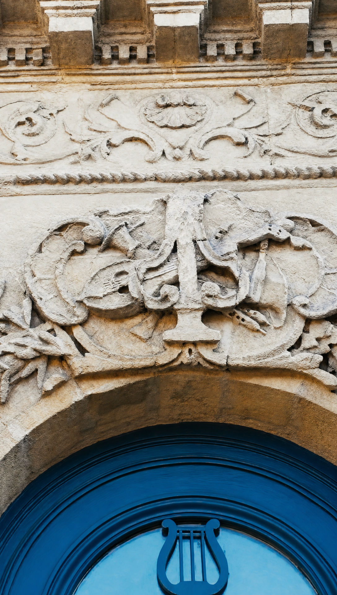 Carved stone scrollwork and a lyre above the arched blue front door