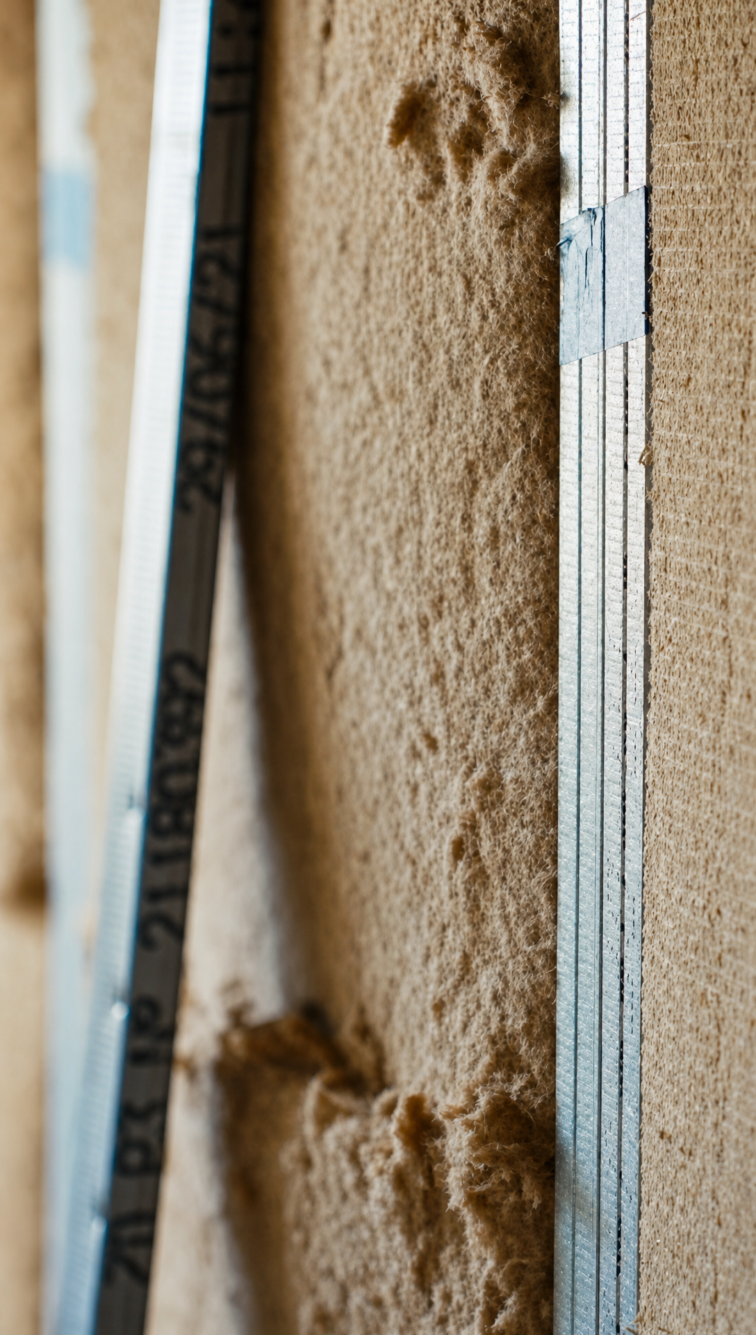 Close view of wood fibre insulation swelling out past the face of a metal stud