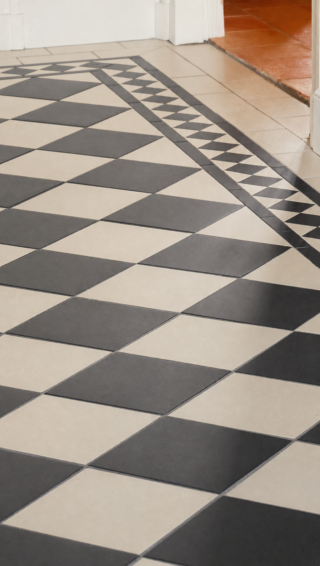 Black and white chequered tiled floor in the hallway with a dark border running along the edge