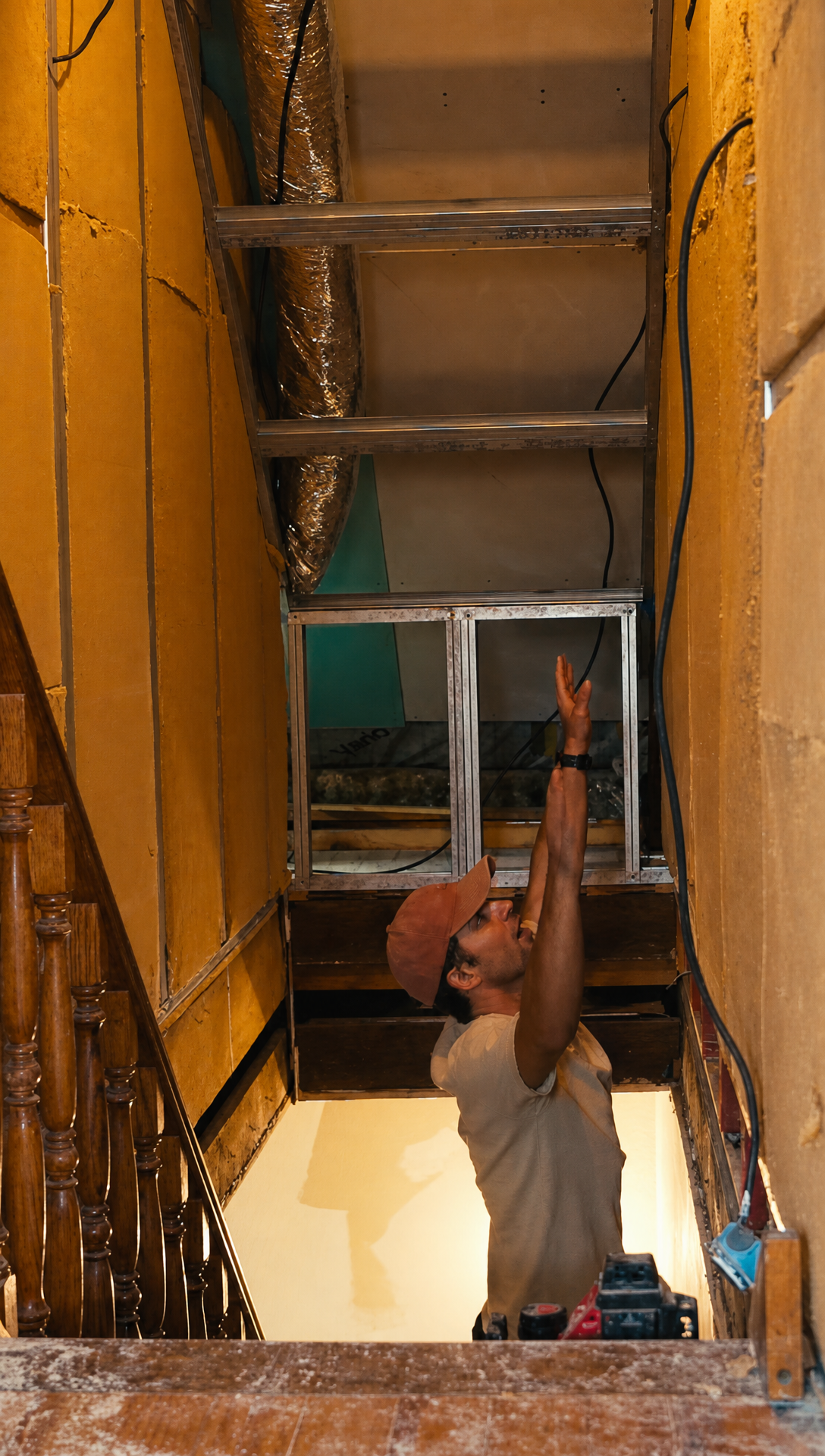 Hugo standing on the attic stairs, reaching up towards the top of the stairwell walls, which are well out of reach