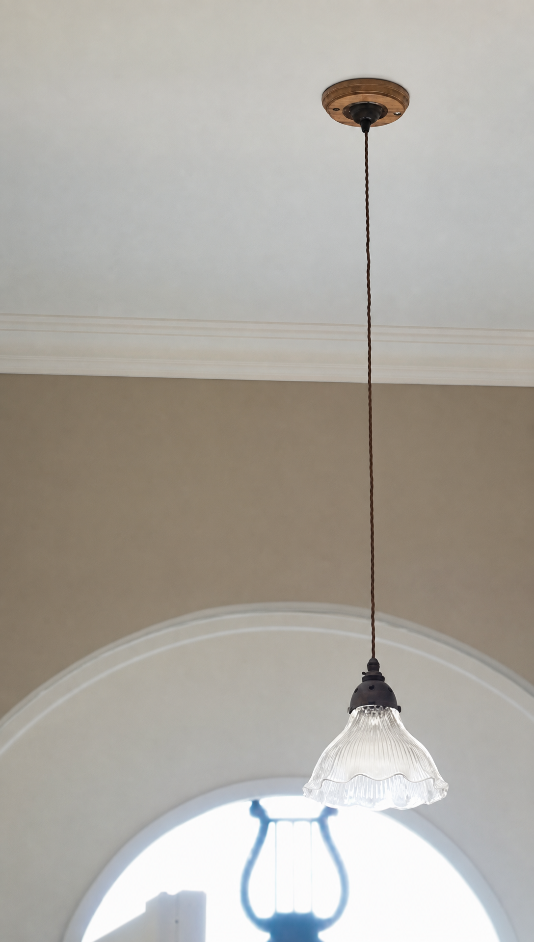 An antique glass pendant light hanging in front of the arched window above the front door