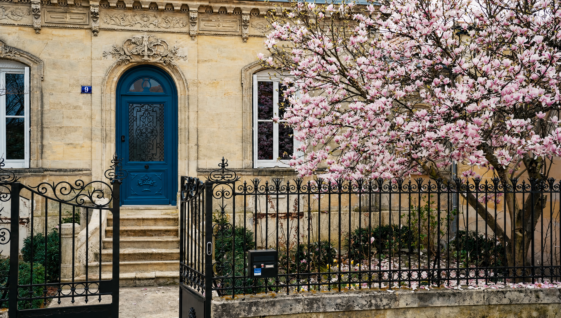 The front of the house in spring with the magnolia in full pink bloom beside the railings