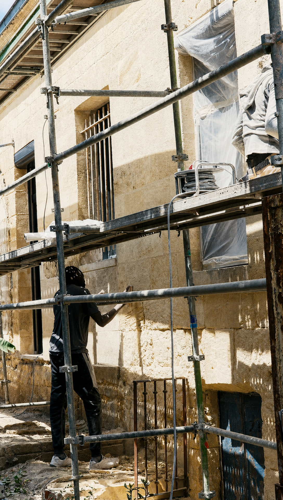 Stonemasons working on scaffolding against the back wall of the house